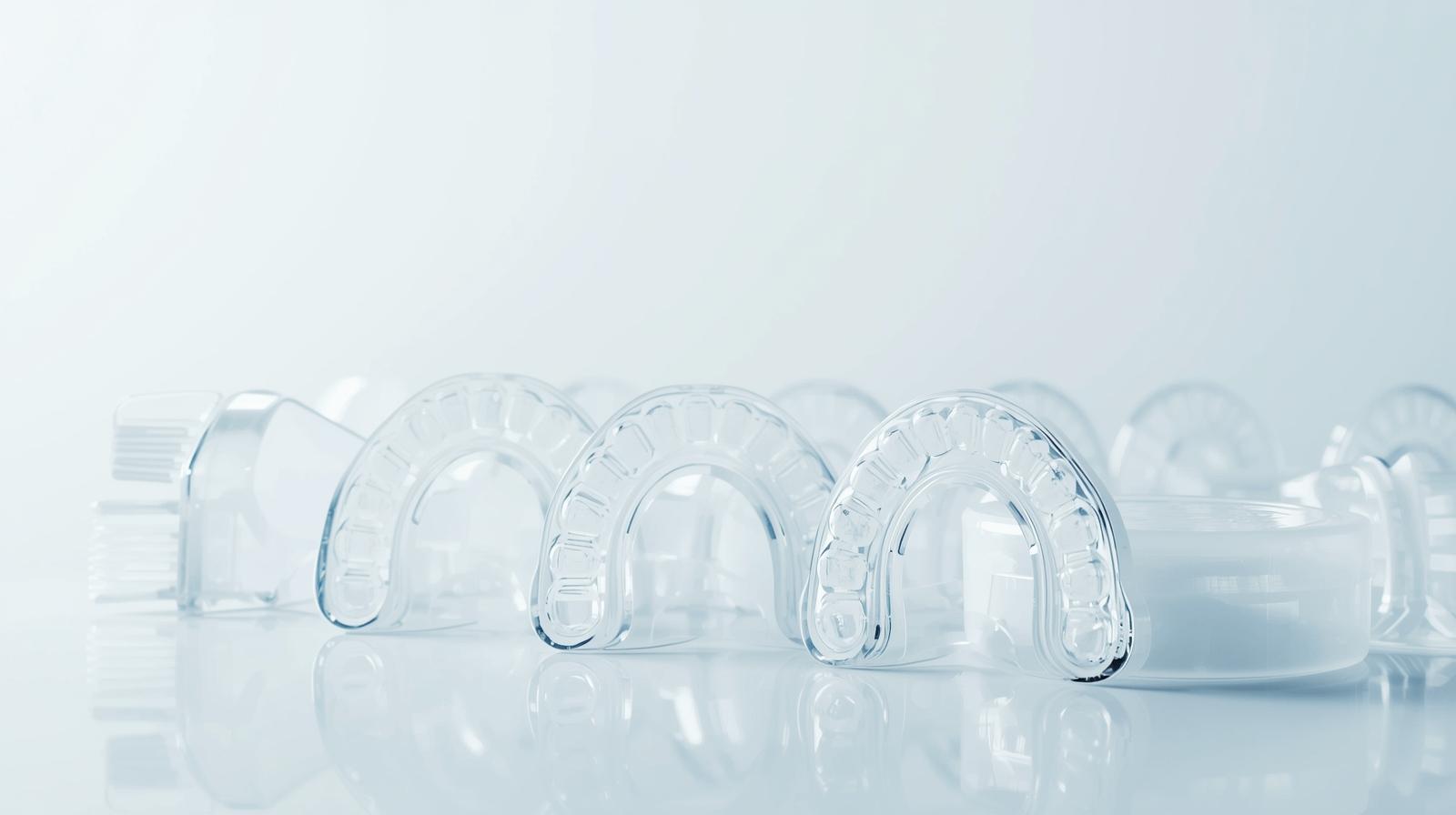白と淡いブルーの背景に歯ブラシとリテーナーが並べられた清潔感あるイメージ写真。矯正後のケアを象徴する静かな雰囲気